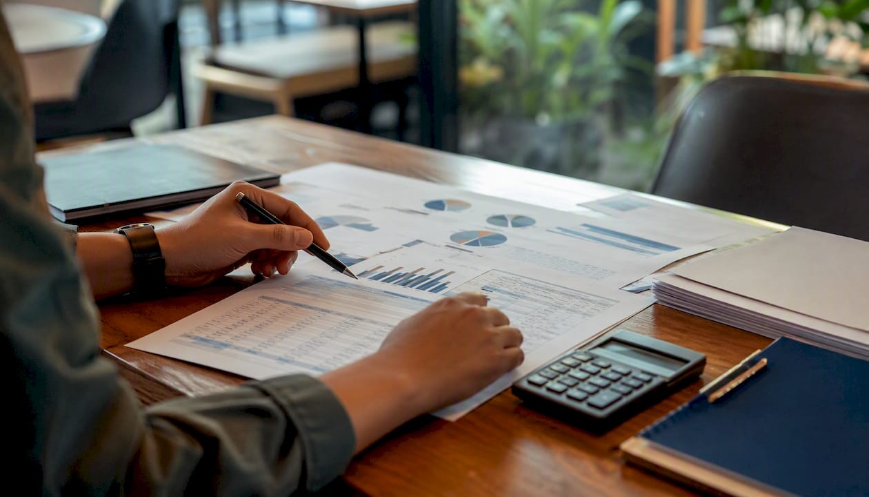 Hands examining cost variance data with magnifier