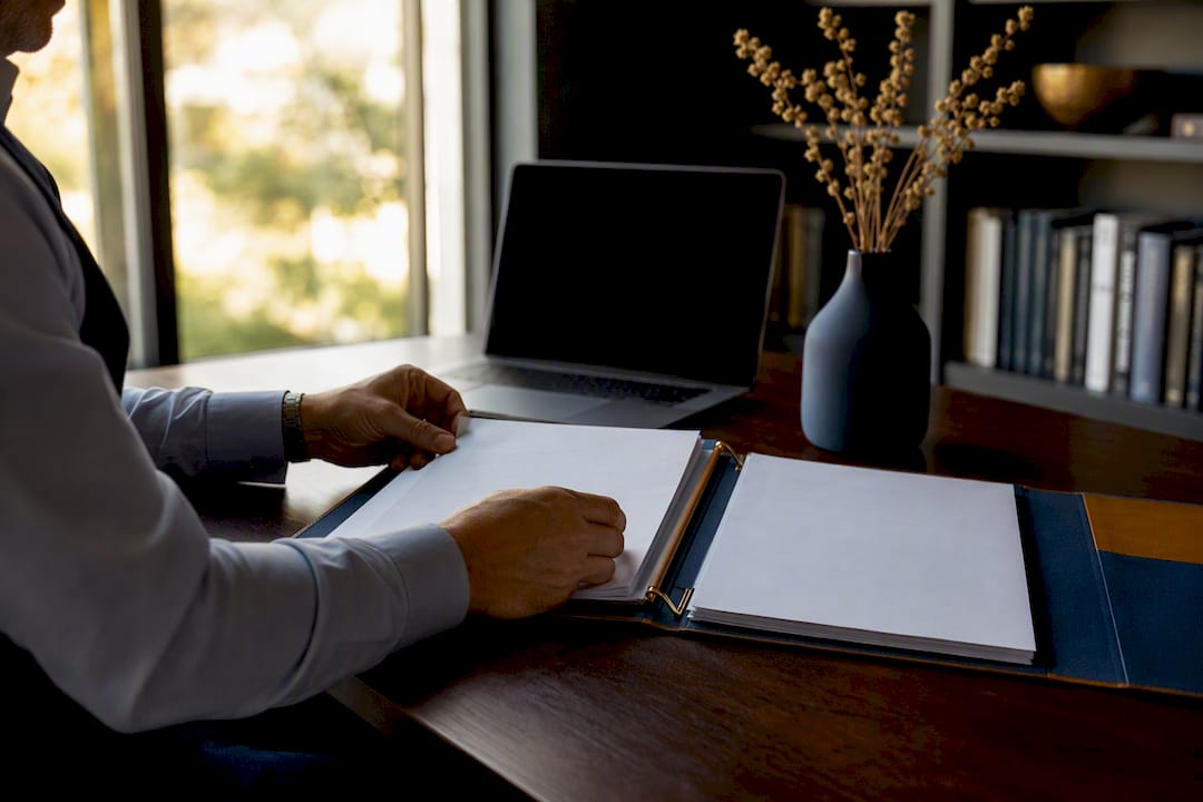 Hands arranging operational playbooks on executive desk