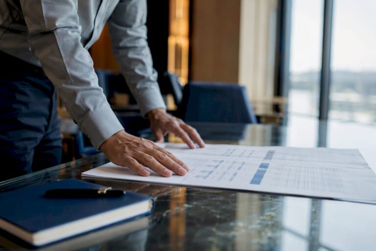 Hands unrolling earnout contract exhibit on desk