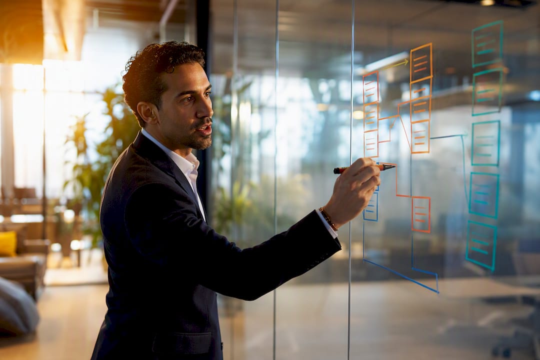 Hand sketching tiered payout structure on glass board